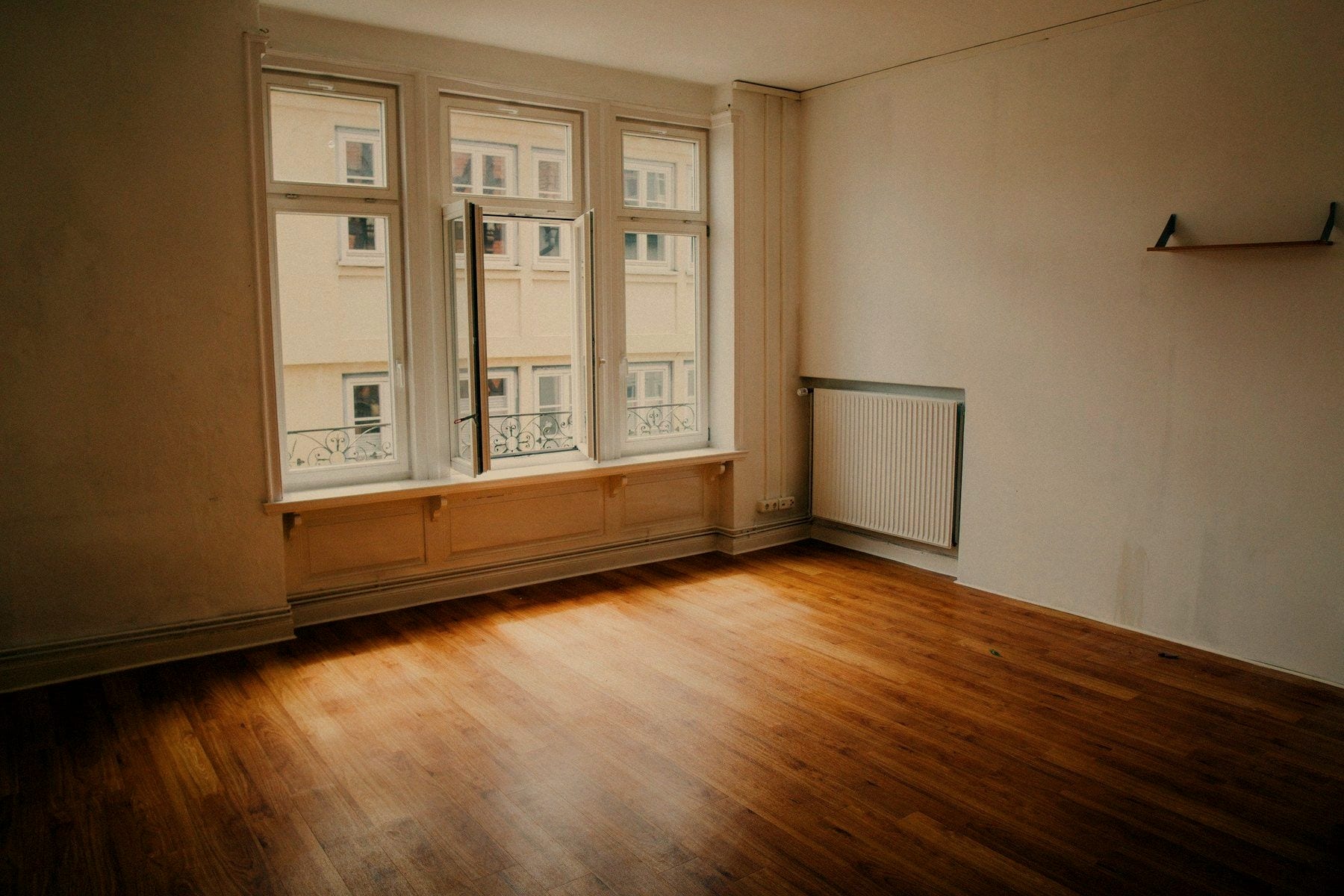 The front room in the morning, light across bare boards, tall windows onto the street.